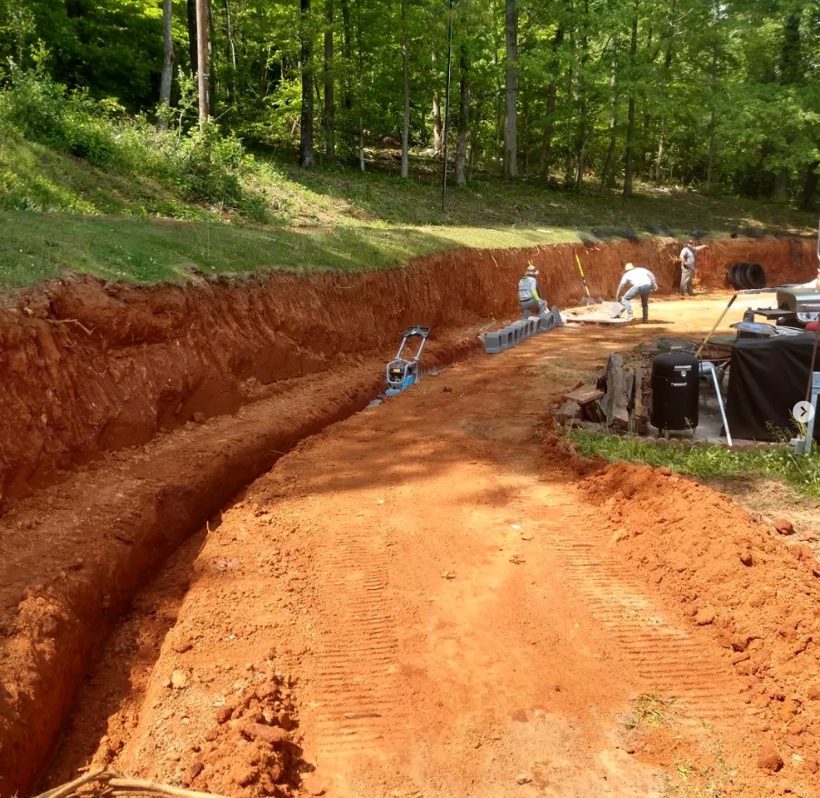 Excavated site with trench along a red clay slope